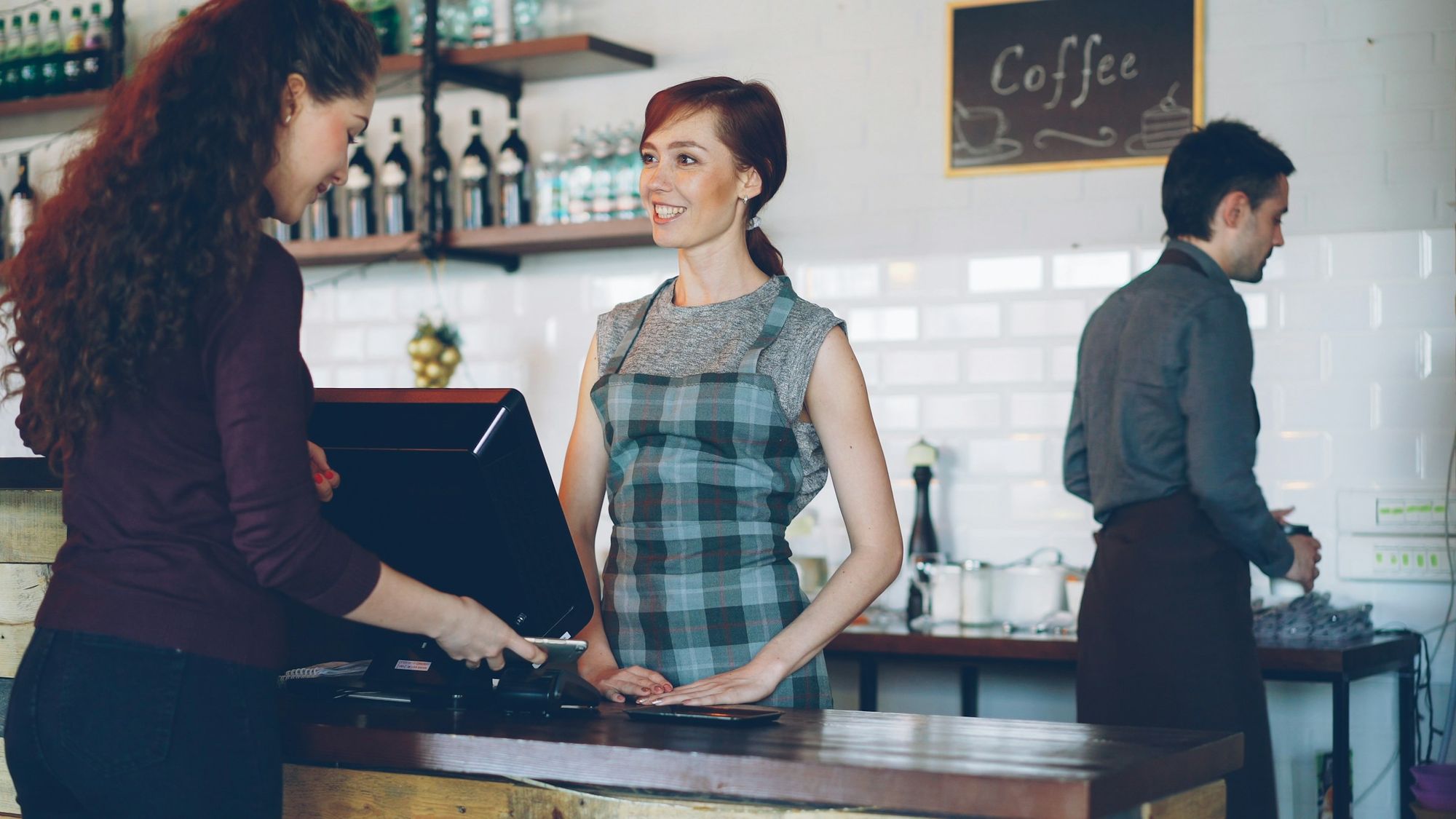 Café attendant completing a customer's payment at the counter.